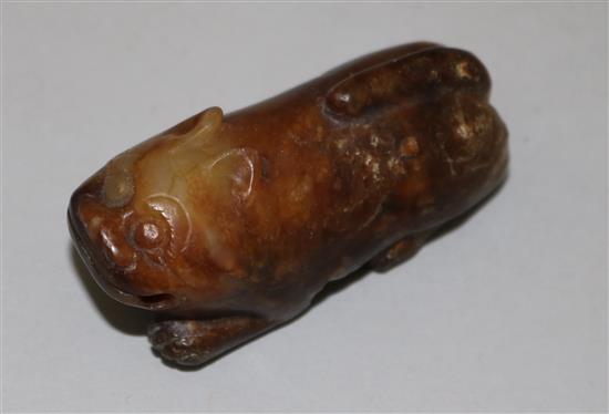 A Chinese yellow and brown jade figure of a recumbent of a lion dog, Ming dynasty or earlier, 5.7cm, calcification